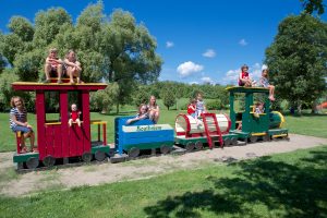 Kids climbing on a wooden play structure at a lakeside resort.