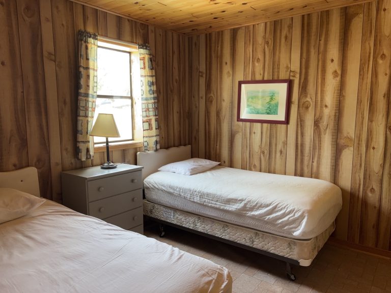 Interior of wood-panelled cottage, with two beds and a window
