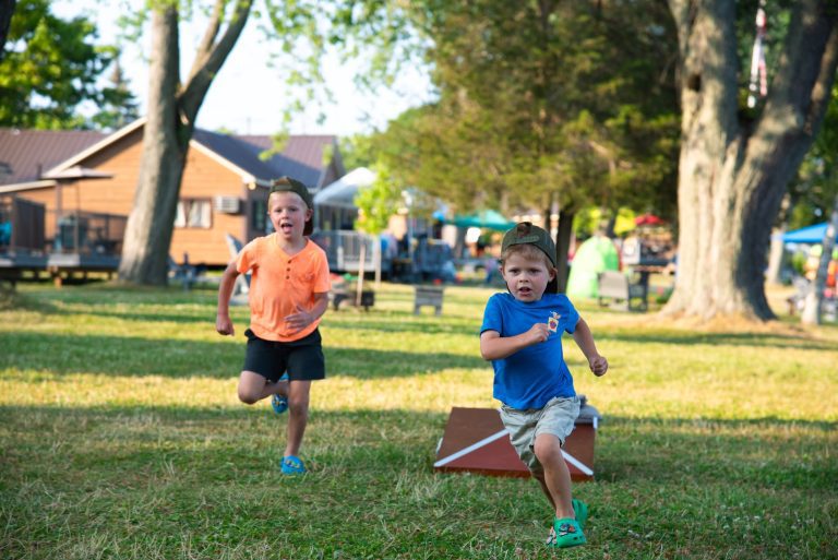 A pair of children sprint across a green lawn