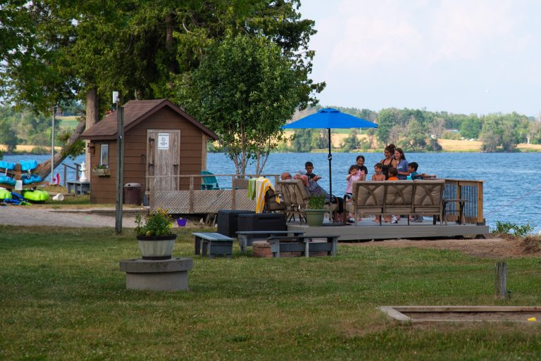View of a cottage deck with people gathered on it, seen from a distance
