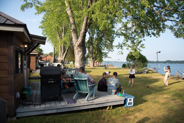 View looking out across a cottage patio towards a large tree and lake