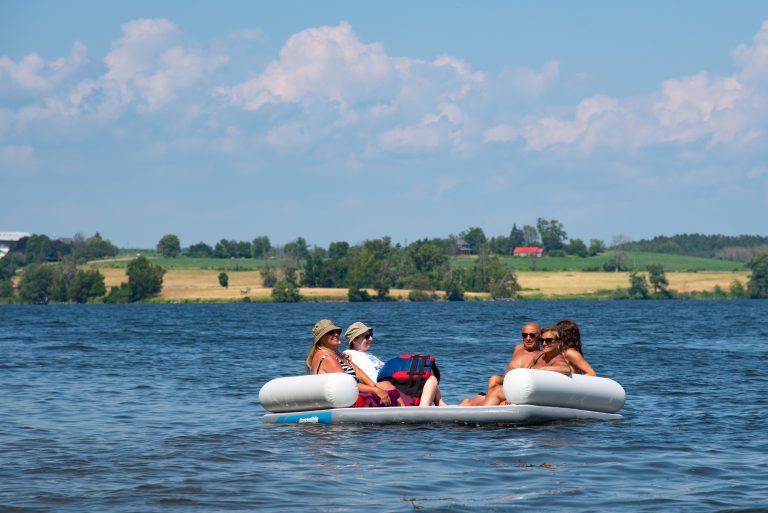 A group of people lounge in a hot tub-shaped inflatable in a lake
