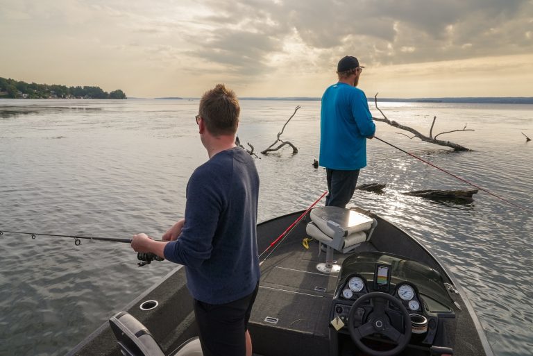 Two people fish from the bow of a boat on a lake